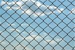 Chain link wired fence pattern against blue sky.
