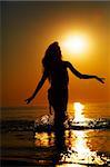 Silhouette of a girl in the water at sunset. Natural light and dark. Artistic colors added. Horizontal photo