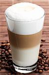 latte macchiato with coffee beans on wooden background