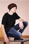 The teenager with a skateboard and in a hat isolated on white background