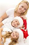 Happy kids and woman relaxing on the white sofa at christmas time - closeup