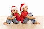 Happy kids on the floor wearing christmas hats, laughing and having fun - isolated