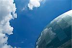 Spherical glass facade reflecting the blue sky and white clouds