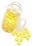 glass bottle with yellow pills on white background