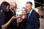 A group of business people looking at a cell phone and laughing