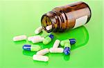 Pill bottle with white and blue pills on green