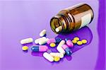 Pill bottle with coloured pills on puple