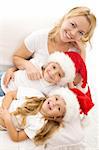 Woman and kids in christmas hats relaxing on the sofa