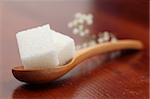 White sugar cubes on a wooden spoon. Shallow dof
