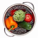 Colander with Fresh Vegetables Including Orange Bell Pepper, Artichoke, Tomatoes and a Cucumber. Isolated on White with a Clipping Path.