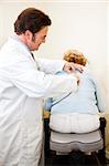Chiropractor using an electronic tool to adjust a patient.