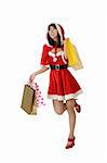 Happy shopping woman walking in Santa Claus clothes isolated over white.
