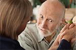 Senior couple at home in kitchen holding hands focusing on man