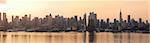 Manhattan urban skyline panorama in New York City with Empire State Building at sunrise over Hudson River