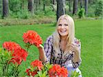 Beautiful gardener woman with red flower bush outdoors