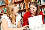 Teen girls in the school library, discussing what they are learning online.