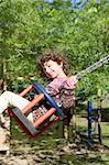 girl swinging on swing happy in trees outdoor up high