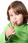 Toddler girl with chubby cheeks eating a sticky lollipop