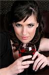 Female model with intense eyes holding a glass of red wine