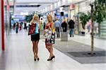 two young beautiful and elegant woman inside a commercial center go for shopping with shoppingbags