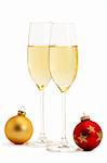 two glasses with champagne and one red and one golden christmas balls on white background