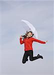 Girl with a white umbrella jumping against the sky