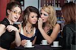 Four girls sharing secrets in a small cafe