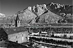 black and white view on Alpine S.Quirico Church in winter, Ossola valley and mountains in background, Domodossola, Italy