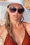 beautiful woman in a hat and sunglasses on the beach in a bikini
