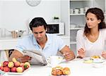 Businessman reading the newspaper with his girlfriend during breakfast at home