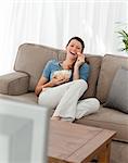 Cheerful woman watching television and eating pop corn in the living-room