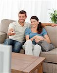 Happy man changing channel while watching television with his wife at home