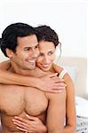Passionate woman hugging her boyfriend sitting on their bed at home