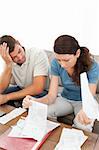 Stressed man and woman looking at their bills in the living room at home