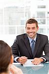 Cheerful businessman during a meeting with a collegue sitting around a table