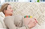 Smiling future mom with baby letters on the belly in the living room