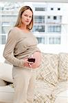 Young pregnant woman holding red wine and a cigarette in the living-room