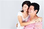 Senior Asian woman and young daughter looking away with smiling, on grey background.