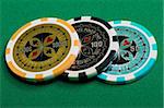 three poker chips on a green background fabric