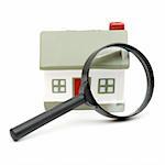 A magnifying glass examining model home. Isolated on white.