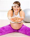 Smiling beautiful pregnant woman doing stretching exercises