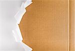 Torn wrapping paper revealing brown cardboard box