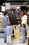 Family with children in shop look at an empty board