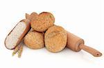 Bread roll stack with wholegrain flour in a scoop and wooden rolling pin with loose wheat, over white background.