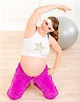 Smiling beautiful pregnant woman doing fitness exercises at living room