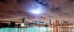 Remember September 11. New York City Manhattan panorama view with Brooklyn Bridge at night with office building skyscrapers skyline illuminated over Hudson River and two light beam in memory of September 11.