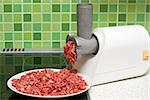 Meat grinder on kitchen, mincemeat on background of the tiled bar