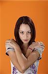 Cute teenager with crossed arms on an orange background