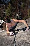 A strong woman struggles up a steep rock face in Squamish British Columbia Canada.