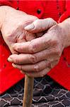 Old woman hands leans on walking stick